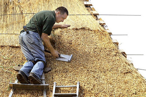 Kevin E. Schmidt/QUAD-CITY TIMES Master thatcher Colin McGhee of Staunton, Va., works on the thatch roof of the German hausbarn being built in Lincoln Park in DeWitt, Iowa.